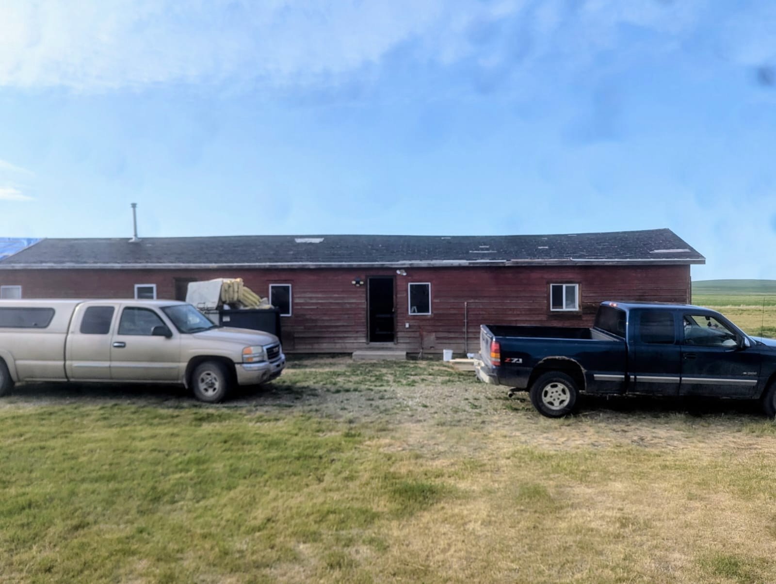 Building before renovation, with two pickup trucks parked in front