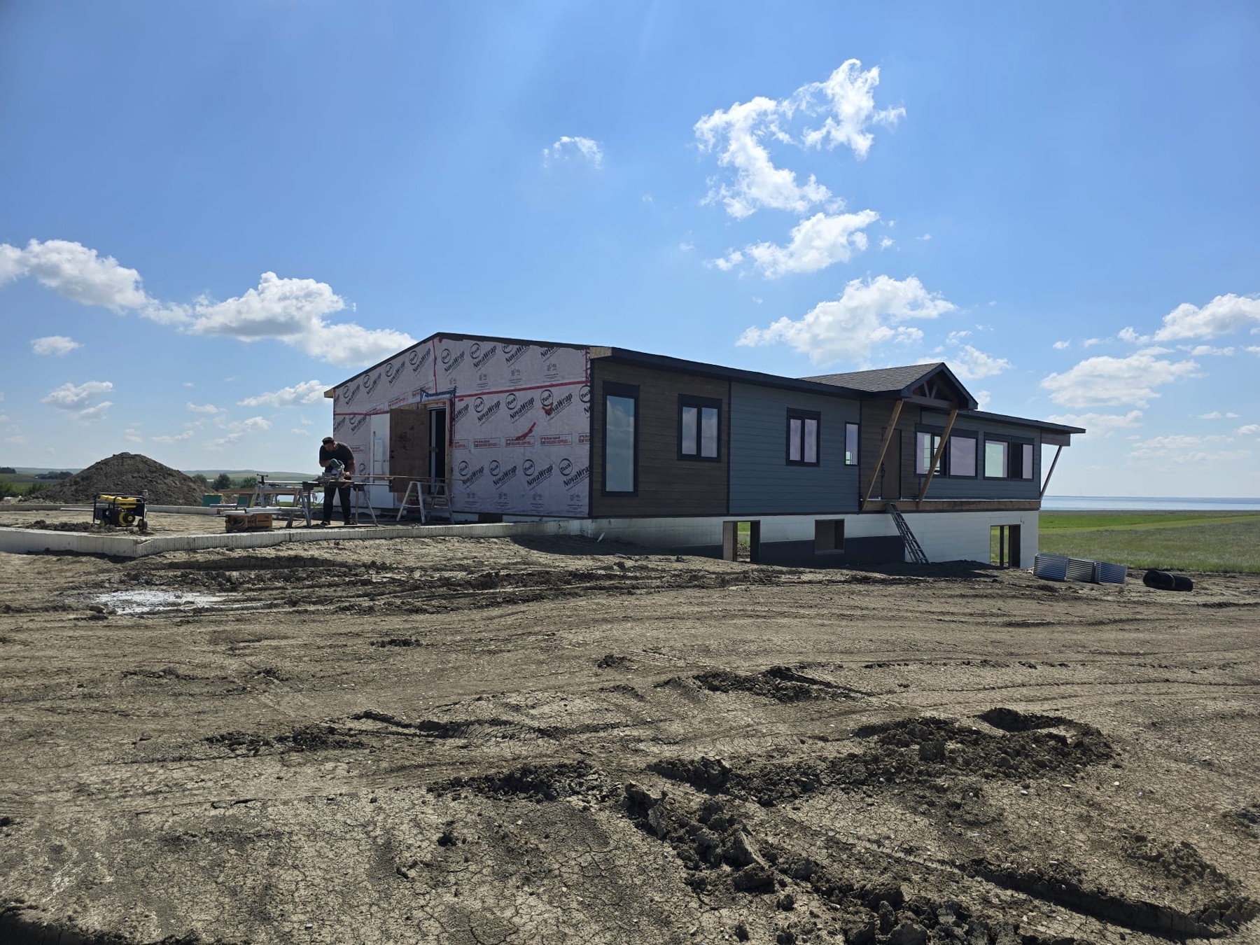 Blue house under construction with large windows and unfinished exterior wall