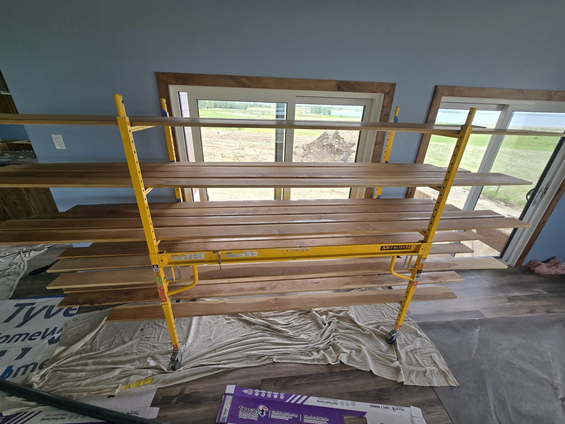 Stained wood trim supported on yellow scaffolding